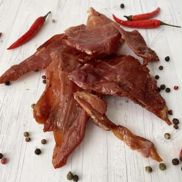 Close-up of sliced MONSI jerky with chili peppers and peppercorns